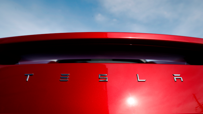 In this April 15, 2018, file photo, the sun shines off the rear deck of a roadster on a Tesla dealer's lot in the south Denver suburb of Littleton, Colo.
