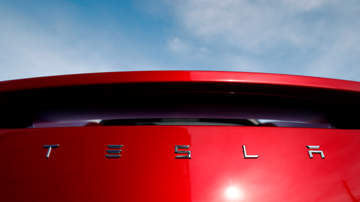 In this April 15, 2018, file photo, the sun shines off the rear deck of a roadster on a Tesla dealer's lot in the south Denver suburb of Littleton, Colo.
