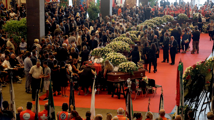 People gather for a funeral service for some of the victims of a collapsed highway bridge, in Genoa's exhibition center Fiera di Genova, Italy, Saturday, Aug. 18, 2018.