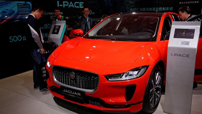 In this April 25, 2018, file photo journalists and visitors look at the Jaguar electric-powered I-Pace model showcases at the China Auto Show during the media day in Beijing.