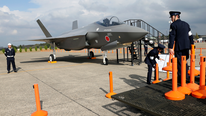 In this Oct. 26, 2014, file photo, Japan Air Self-Defense Force crew members set up cordons to protect a mockup of the F-35 fighter jet during the annual Self-Defense Forces Commencement of Air Review at Hyakuri Air Base, north of Tokyo.