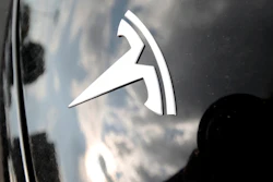 In this July 8, 2018, photo, clouds are reflected above the company logo on the hood of a 2018 Model 3 sedan on display outside a Tesla showroom in Littleton, Colo.