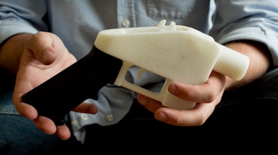 In this May 10, 2013, file photo, Cody Wilson holds what he calls a Liberator pistol that was completely made on a 3-D-printer at his home in Austin, Texas.