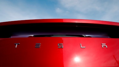 In this April 15, 2018, file photo, the sun shines off the rear deck of a roadster on a Tesla dealer's lot in the south Denver suburb of Littleton, Colo.