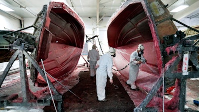 In this July 11, 2018 file photo, workers apply fiberglass to the resin frame of a boat at Regal Marine Industries in Orlando, Fla.
