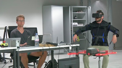 Robotics expert on the Ecole Polytechnique Federal de Lausanne, EPFL team, Matteo Macchini, right, displays the fly controls in a virtual reality scenario as he controls the flight of a drone.