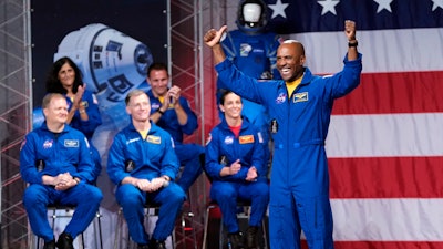 Astronaut Victor Glover raises his arms after being introduced during a NASA event to announce the astronauts assigned to crew the first flight tests and missions of the Boeing CST-100 Starliner and SpaceX Crew Dragon.