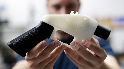 In this Aug. 1, 2018, file photo, Cody Wilson, with Defense Distributed, holds a 3D-printed gun called the Liberator at his shop in Austin, Texas.