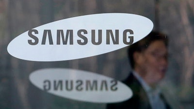 In this April 6, 2018, file photo, an employee walks past logos of the Samsung Electronics Co. at its office in Seoul, South Korea.