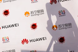 A worker casts a shadow on a board panel at a shopping mall in Beijing, Thursday, Aug, 16, 2018.
