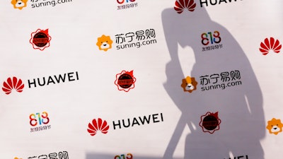 A worker casts a shadow on a board panel at a shopping mall in Beijing, Thursday, Aug, 16, 2018.