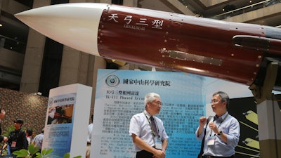 In this Aug. 13, 2015, file photo, two men speak under the Taiwan-made 'Tien-Kung III' surface to air missile during the 2015 Taipei Aerospace and Defense Technology Exhibition in Taipei, Taiwan.