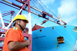 In this Aug. 8, 2018, photo, a worker stands near a container ship at a port in Qingdao in eastern China's Shandong Province.