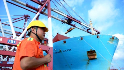 In this Aug. 8, 2018, photo, a worker stands near a container ship at a port in Qingdao in eastern China's Shandong Province.