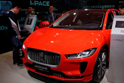 In this April 25, 2018, file photo journalists and visitors look at the Jaguar electric-powered I-Pace model showcases at the China Auto Show during the media day in Beijing.