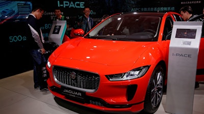 In this April 25, 2018, file photo journalists and visitors look at the Jaguar electric-powered I-Pace model showcases at the China Auto Show during the media day in Beijing.