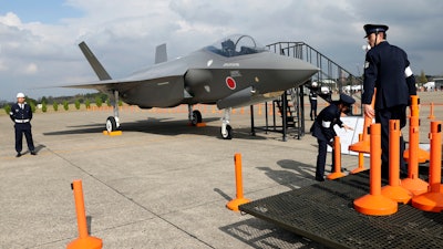 In this Oct. 26, 2014, file photo, Japan Air Self-Defense Force crew members set up cordons to protect a mockup of the F-35 fighter jet during the annual Self-Defense Forces Commencement of Air Review at Hyakuri Air Base, north of Tokyo.