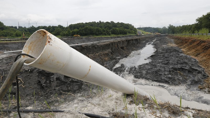 In this Friday June 26, 2015 file photo, a drain pipe sticks out of a coal ash retention pond at the Dominion Power’s Possum Point Power Station in Dumfries, Va.