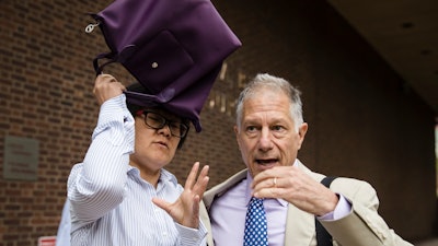 Yu Xue, left, accompanied by her attorney Peter Zeidenberg attempts to block her face with her bag as they exit the federal courthouse in Philadelphia, Friday, Aug. 31, 2018.