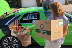 In this Aug. 29, 2018 photo, customer Maureen Blaskovich grabs a coconut water from the backseat window of a self-driving car in San Jose, Calif.