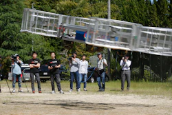 In this Saturday, June 3, 2017, file photo, Tsubasa Nakamura, project leader of Cartivator, third from left, watches the flight of the test model of the flying car on a former school ground in Toyota, central Japan.