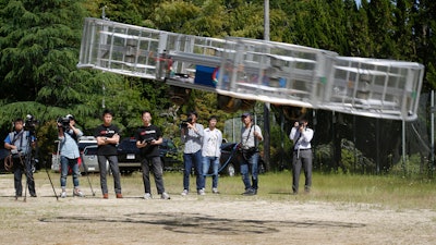 In this Saturday, June 3, 2017, file photo, Tsubasa Nakamura, project leader of Cartivator, third from left, watches the flight of the test model of the flying car on a former school ground in Toyota, central Japan.