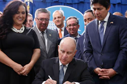 State Sen. Kevin de Leon, D-Los Angeles, right, watches as Gov. Jerry Brown, center, signs his environmental measure SB100 into law, Monday, Sept. 10, 2018, in Sacramento, Calif.
