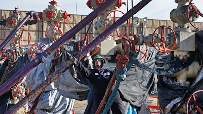 In this March 25, 2014 file photo, a worker adjusts pipes during a hydraulic fracturing operation at a well pad near Mead, Colorado.