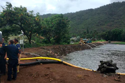 Officials pump water from a reservoir where a dam came close to overflowing in Honolulu on Thursday, Sept. 13, 2018.