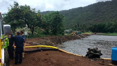 Officials pump water from a reservoir where a dam came close to overflowing in Honolulu on Thursday, Sept. 13, 2018.