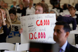 Benjamin Tuggy holds a sign while listening to speakers during the first of three public hearings on the Trump administration's proposal to roll back car-mileage standards in a region with some of the nation's worst air pollution Monday, Sept. 24, 2018 in Fresno, Calif.