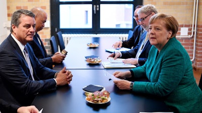 World Trade Organization chief Roberto Acevedo, left, and German Chancellor Angela Merkel hold talks on the sidelines of a conference organized by the Federation of German Industries in Berlin Tuesday, Sept. 25, 2018.