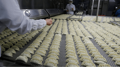 In this July 18, 2018, photo, workers inspect dumplings on a conveyor belt that are made at an automated factory of CJ CheilJedang Corp. in Incheon, South Korea. South Korea’s largest food company is making a multimillion-dollar bet on “mandu,” developing its own machines to automate the normally labor-intensive production of the Korean dumpling and building factories around the world.