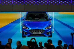 In this April 25, 2018, photo, visitors and journalists gather near a Ford Focus on display at the Ford exhibit during the media day for the China Auto Show in Beijing. Ford won't be moving production of a hatchback wagon to the United States from China, despite President Donald Trump's claim Sunday, Sept. 9, 2018 that his taxes on Chinese imports mean the Focus Active can be built in America.