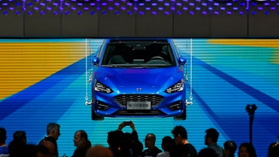 In this April 25, 2018, photo, visitors and journalists gather near a Ford Focus on display at the Ford exhibit during the media day for the China Auto Show in Beijing. Ford won't be moving production of a hatchback wagon to the United States from China, despite President Donald Trump's claim Sunday, Sept. 9, 2018 that his taxes on Chinese imports mean the Focus Active can be built in America.