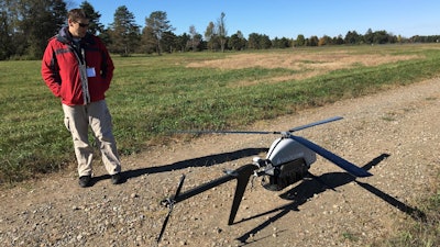 In this Oct. 17, 2017 photo, Nick Brown, a drone pilot for Pulse Aerospace of Lawrence, Kan., stands beside a Pulse Vapor unmanned aircraft at Griffiss International Airport in Rome, N.Y.