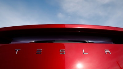 In this April 15, 2018, file photo, the sun shines off the rear deck of a roadster on a Tesla dealer's lot in the south Denver suburb of Littleton, Colo.