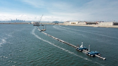 In this Monday, Aug. 27, 2018 photo provided by The Ocean Cleanup, a long floating boom that will be used to corral plastic litter in the Pacific Ocean is assembled in Alameda, Calif. Engineers will deploy a trash collection device to corral plastic litter floating between California and Hawaii in an attempt to clean up the world's largest garbage patch. The 2,000-foot (600-meter) long floating boom will be towed Saturday, Sept. 8, 2018, from San Francisco to the Great Pacific Garbage Patch, an island of trash twice the size of Texas.