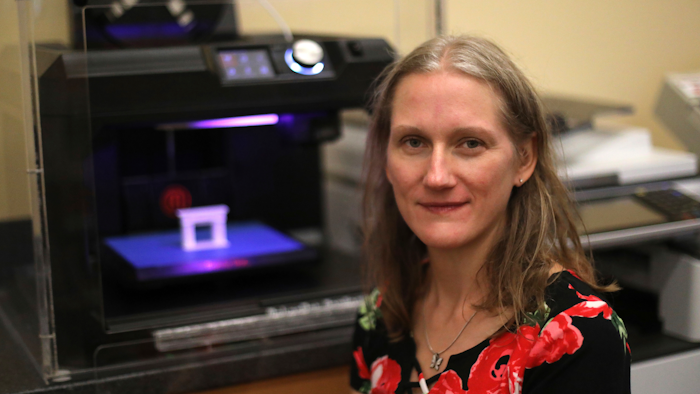 In this Sept. 19, 2018, photo, Patty Krncevic sits next to the 3D printer that she used at the Oregon Branch Library to make part of a cast replica that has a footprint of her stillborn daughter on it, in Oregon, Ohio.