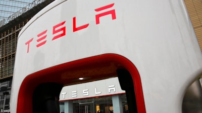 In this April 5, 2018, file photo, a sales person stands inside a Tesla electric vehicle showroom in Beijing.