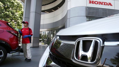 In this July 31, 2018, file photo, an employee of Honda Motor Co. cleans a Honda car displayed at its headquarters in Tokyo.