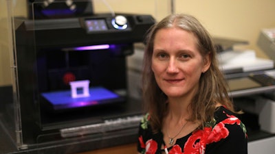 In this Sept. 19, 2018, photo, Patty Krncevic sits next to the 3D printer that she used at the Oregon Branch Library to make part of a cast replica that has a footprint of her stillborn daughter on it, in Oregon, Ohio.