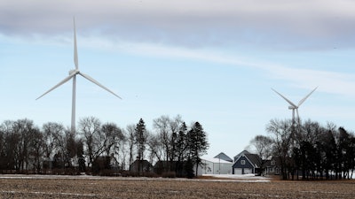 In this Feb. 2, 2018 file photo, wind turbines stand over a farmhouse near Northwood, Iowa.