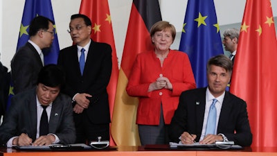 In this July 9, 2018 file photo German Chancellor Angela Merkel and Chinese Premier Li Keqiang attend a contracts signing ceremony between German car maker BMW CEO Harald Krueger and Qi Yumin CEO of the Brilliance Group during a meeting in the chancellery in Berlin.