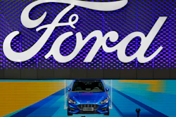 In this April 25, 2018, photo, visitors and journalists gather near a Ford Focus on display at the Ford exhibit during the media day for the China Auto Show in Beijing.