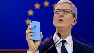Apple CEO Tim Cook holds up an iPhone as he speaks during a data privacy conference at the European Parliament in Brussels, Wednesday, Oct. 24, 2018.