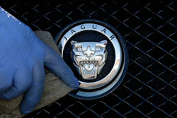 In this file photo taken on Wednesday, Sept. 28, 2016, a worker polishes a Jaguar logo on a car at a Jaguar dealer in London.