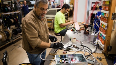 In this Thursday, Oct. 18, 2018, photo Sarmad Eskandar, left, and Mustpha Damen work on electrical components at the Howard McCray's commercial refrigeration manufacturing facility in Philadelphia.