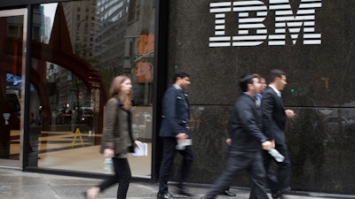 In this April 26, 2017, file photo, pedestrians walk past the IBM logo displayed on the IBM building in New York.