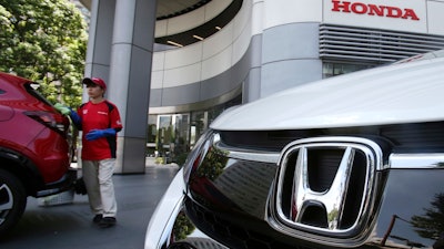 In this July 31, 2018, file photo, an employee of Honda Motor Co. cleans a Honda car displayed at its headquarters in Tokyo.